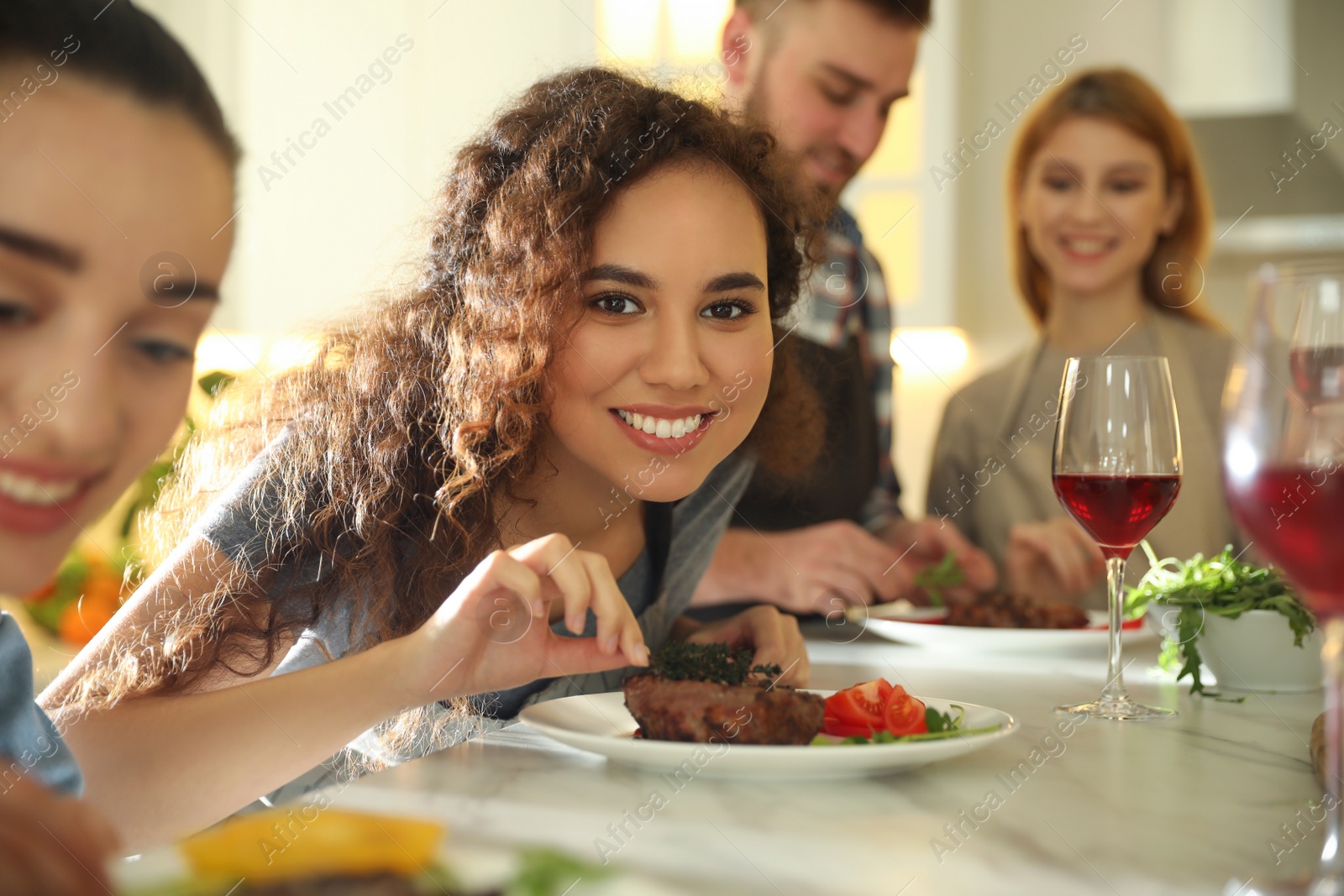 Photo of Young African-American woman serving food in crowded kitchen. Cooking class