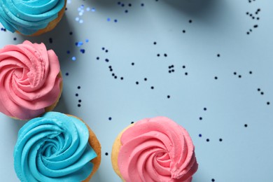 Photo of Delicious cupcakes with bright cream and confetti on light blue background, flat lay. Space for text