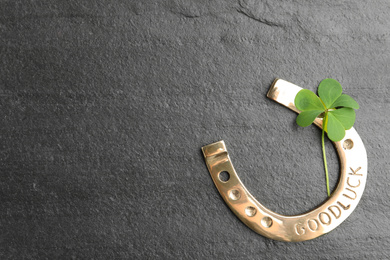 Photo of Clover leaf and horseshoe on grey stone table, flat lay with space for text. St. Patrick's Day celebration