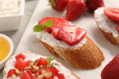 Photo of Delicious ricotta bruschettas with strawberry and mint on grey table