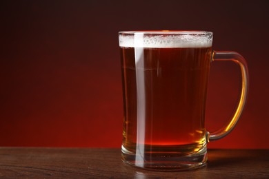 Photo of Mug with fresh beer on wooden table against color background, closeup. Space for text