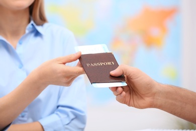 Photo of Female manager giving passport with ticket to client in travel agency