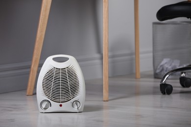 Photo of White electric fan heater on floor at home. Space for text