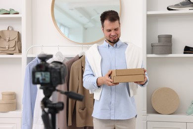 Smiling fashion blogger with cardboard boxes recording video at home