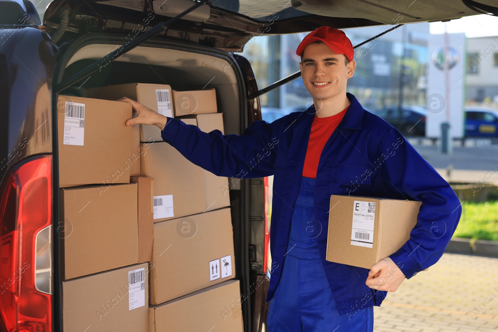 Photo of Courier with parcel near delivery van outdoors