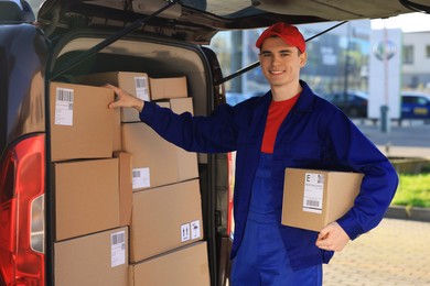Photo of Courier with parcel near delivery van outdoors