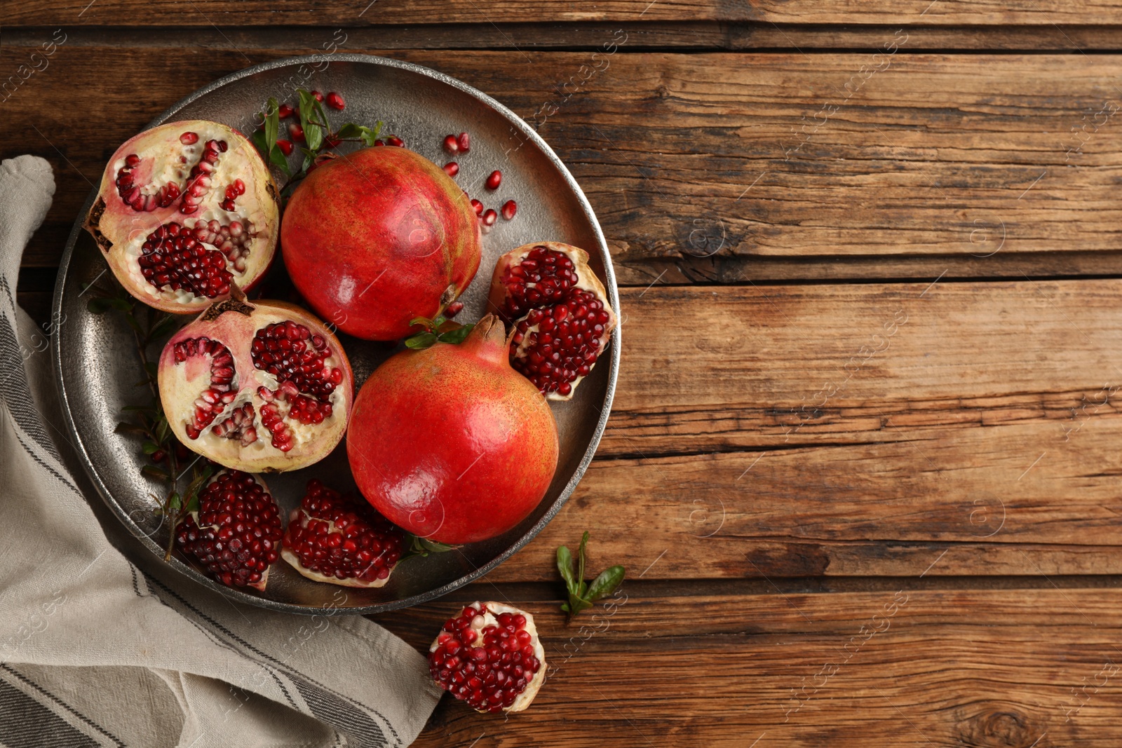 Photo of Delicious ripe pomegranates on wooden table, flat lay. Space for text