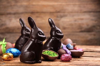 Dark chocolate Easter bunnies and eggs on wooden table. Space for text