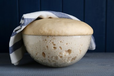 Photo of Bowl of fresh yeast dough on grey wooden table