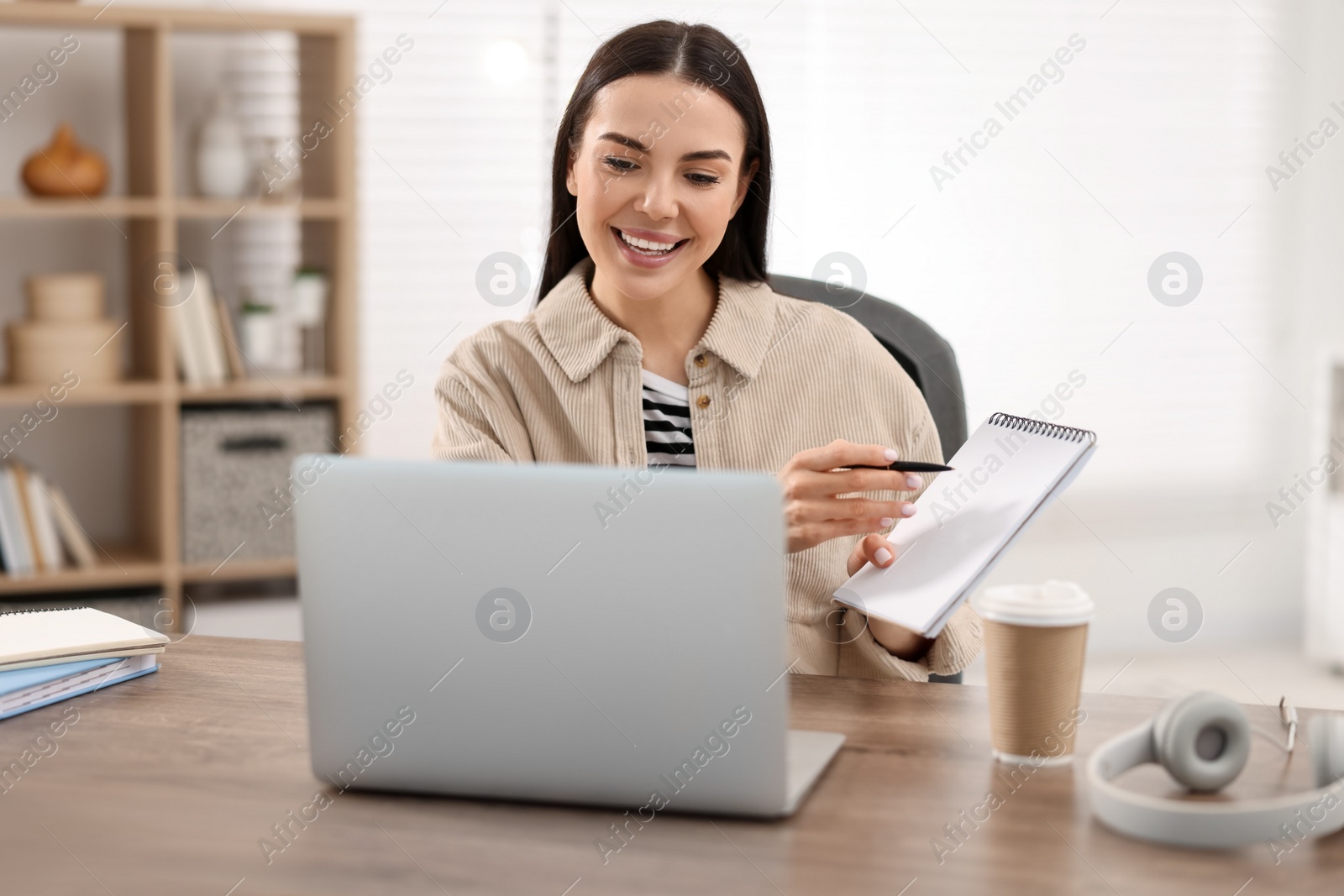 Photo of Young woman using video chat during webinar at table in room