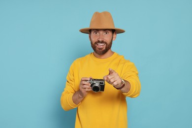 Photo of Man with camera on light blue background. Interesting hobby
