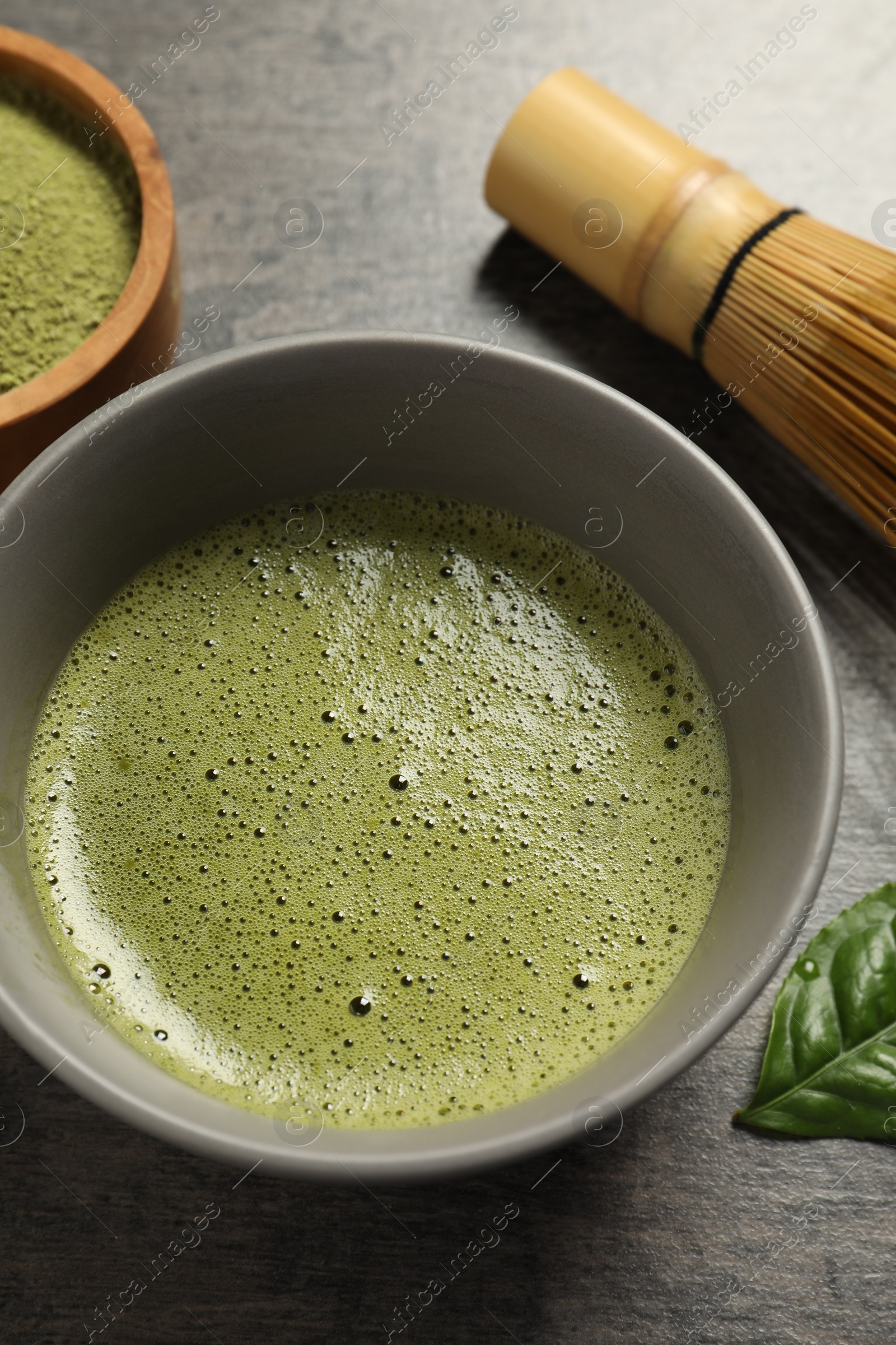 Photo of Cup of fresh matcha tea on dark grey table, above view