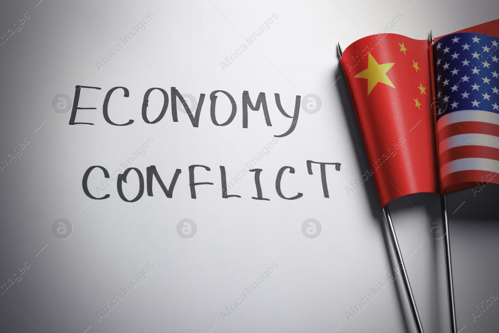 Photo of USA and China flags near words ECONOMY CONFLICT on white background, flat lay