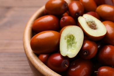 Fresh Ziziphus jujuba fruits in wooden bowl on table, closeup