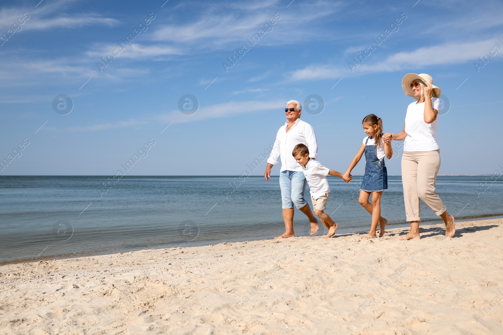 Photo of Cute little children with grandparents spending time together on sea beach