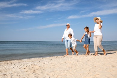 Photo of Cute little children with grandparents spending time together on sea beach