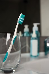 Photo of Light blue toothbrush in glass holder on washbasin