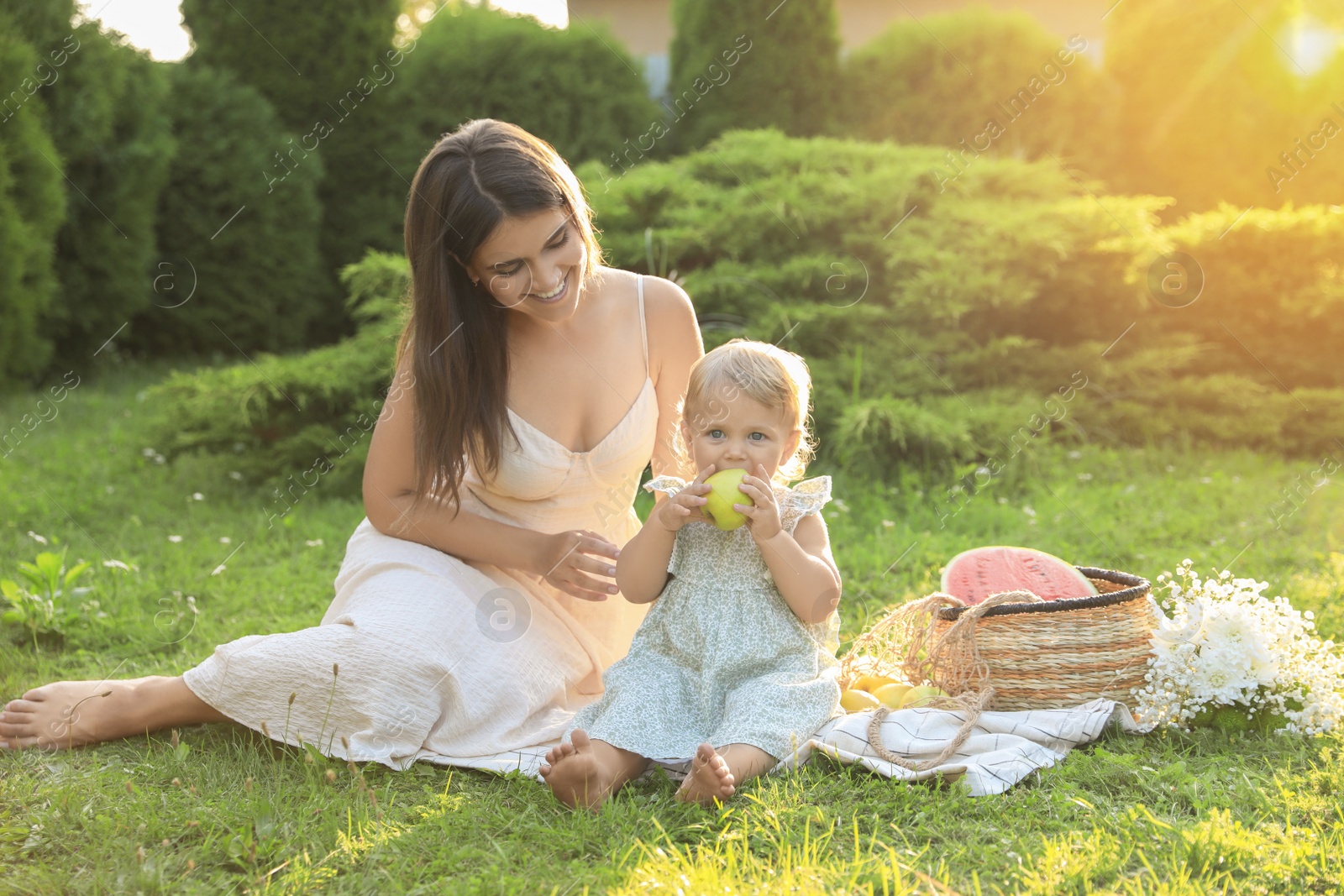 Photo of Mother with her baby daughter having picnic in garden on sunny day