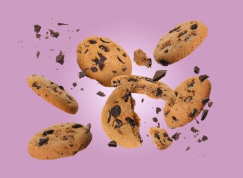 Tasty chocolate chip cookies falling on dusty pink background