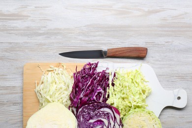 Photo of Different types of cut cabbage and knife on white wooden table, flat lay. Space for text