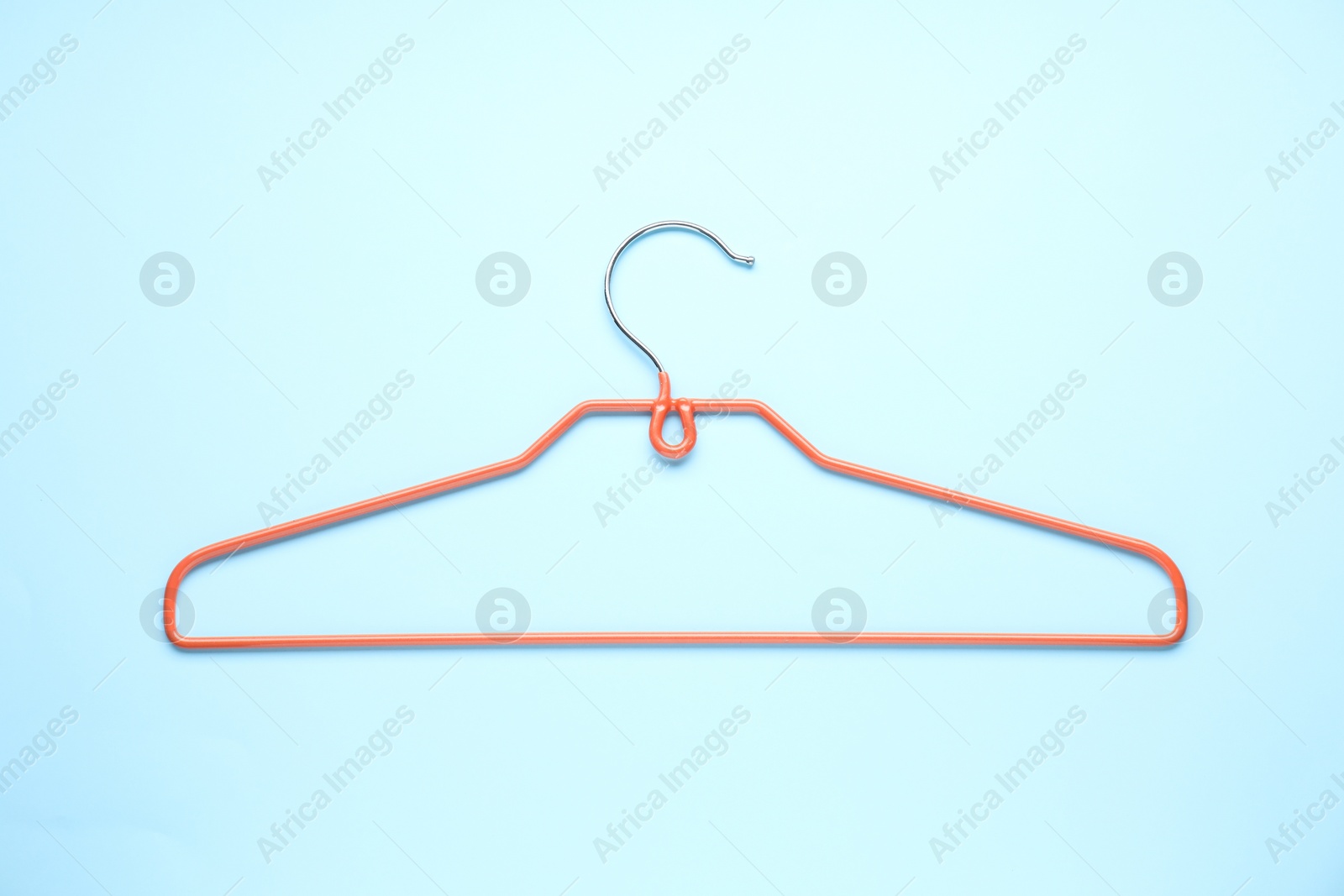 Photo of Empty orange hanger on light blue background, top view