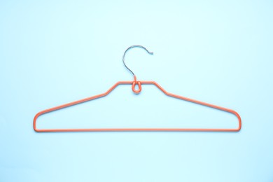 Photo of Empty orange hanger on light blue background, top view