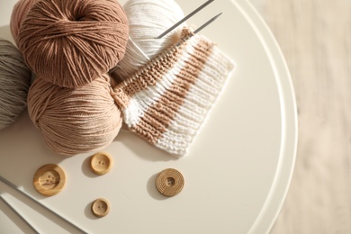 Photo of Yarn balls, buttons and knitting needles on white table, flat lay. Creative hobby