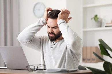 Photo of Man suffering from headache at workplace in office