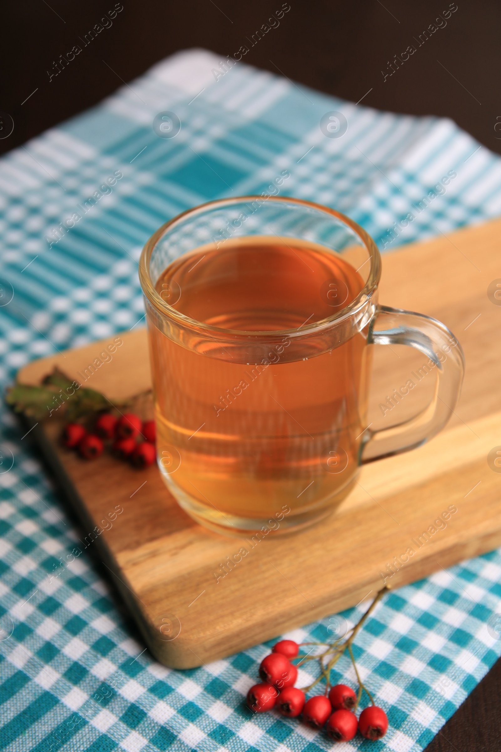 Photo of Cup with hawthorn tea and berries on table