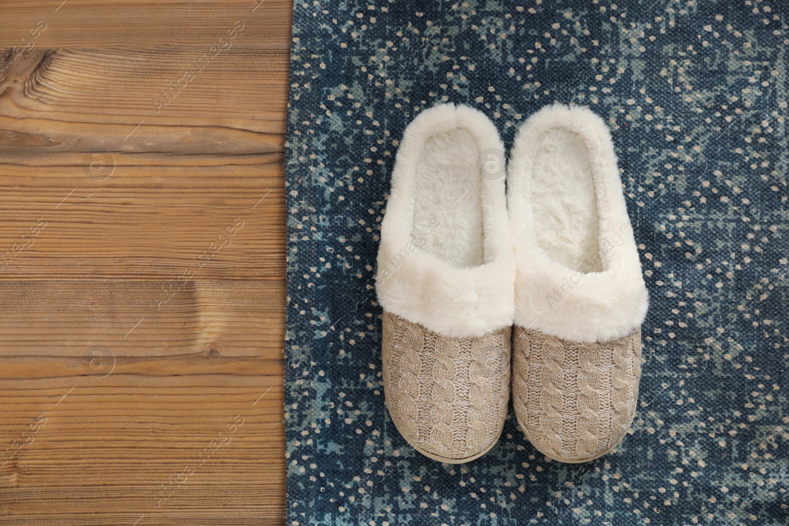 Pair of beautiful soft slippers and rug on wooden floor, top view. Space for text Photo of Pair of beautiful soft slippers and rug on wooden floor, top view. Space for text