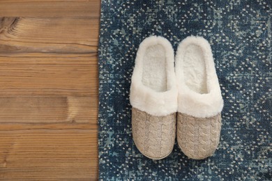 Photo of Pair of beautiful soft slippers and rug on wooden floor, top view. Space for text