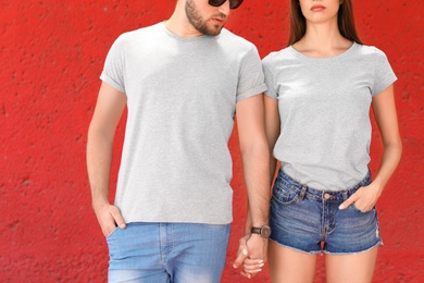 Photo of Young couple wearing gray t-shirts near color wall on street