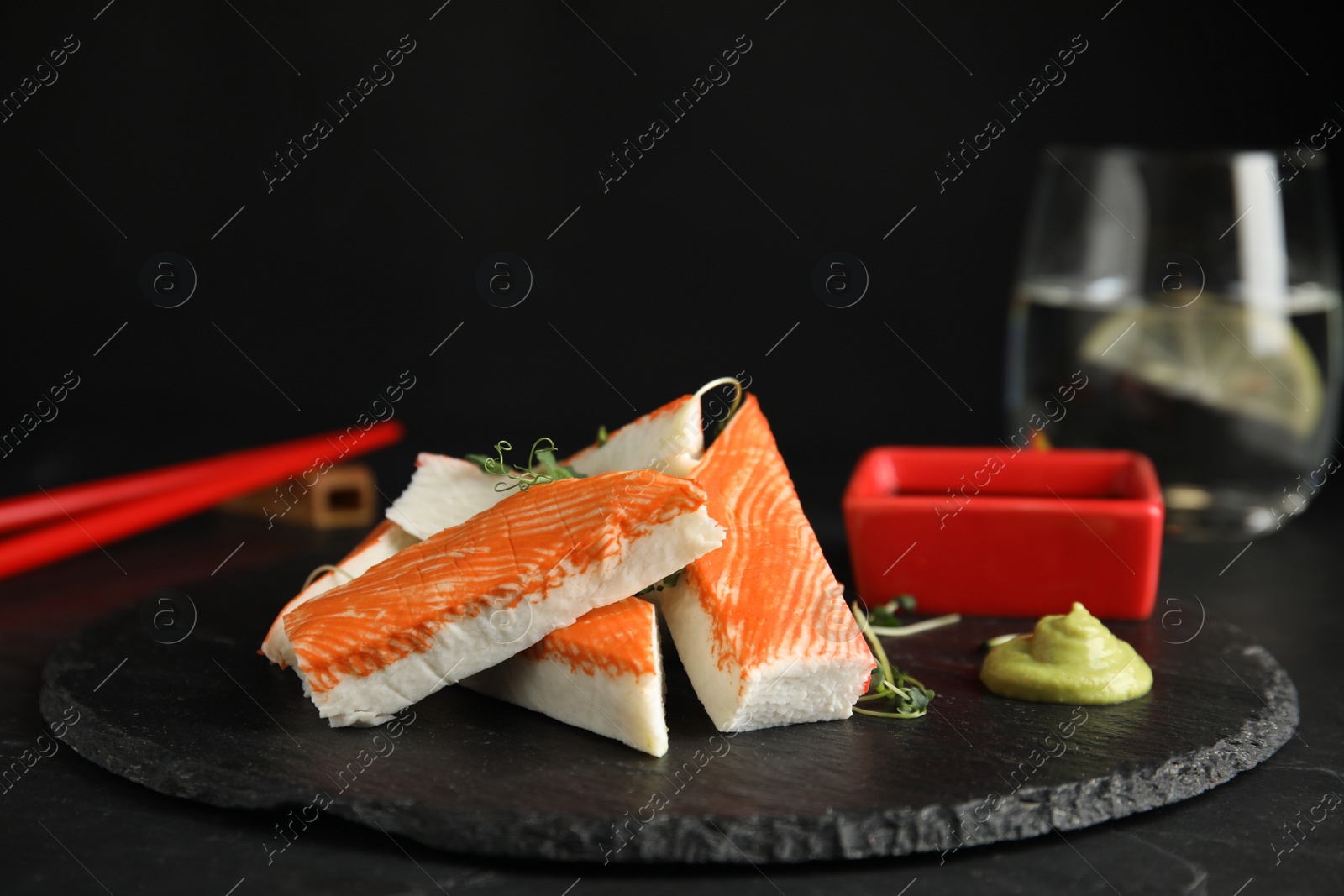 Photo of Fresh crab sticks with sauce served on black table, closeup