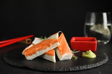 Fresh crab sticks with sauce served on black table, closeup