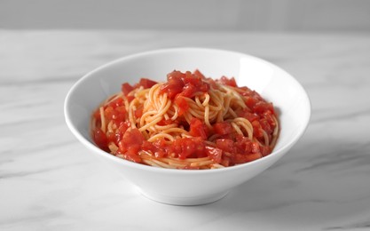 Bowl of delicious pasta with tomatoes on white marble table indoors