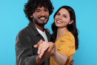 Photo of International dating. Happy couple dancing on light blue background