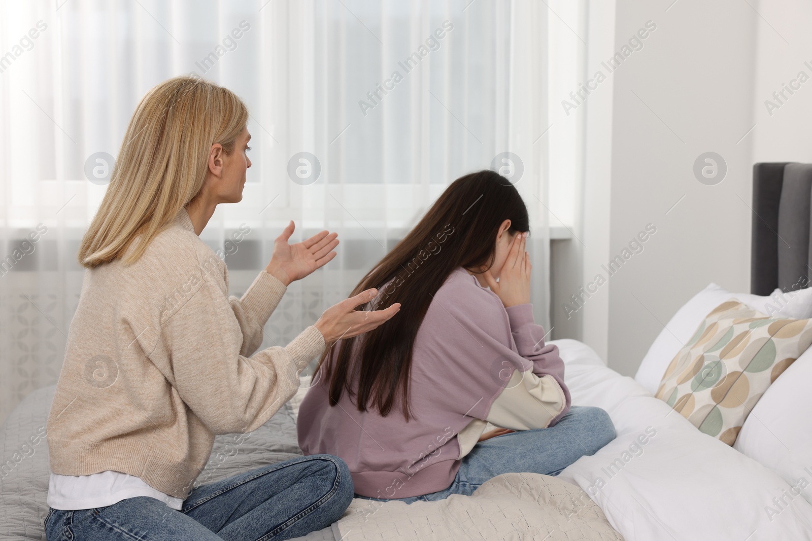 Photo of Mother consoling her upset daughter in bedroom. Teenager problems