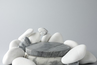 Photo of Presentation for product. Stone podium and pebbles on light grey background. Space for text