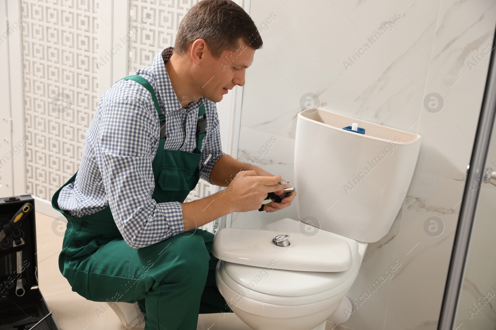 Photo of Professional plumber repairing toilet bowl in bathroom