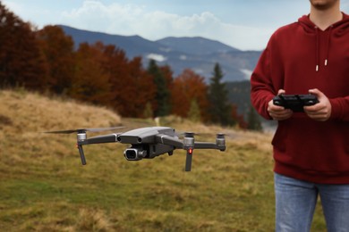 Man operating modern drone with remote control in mountains