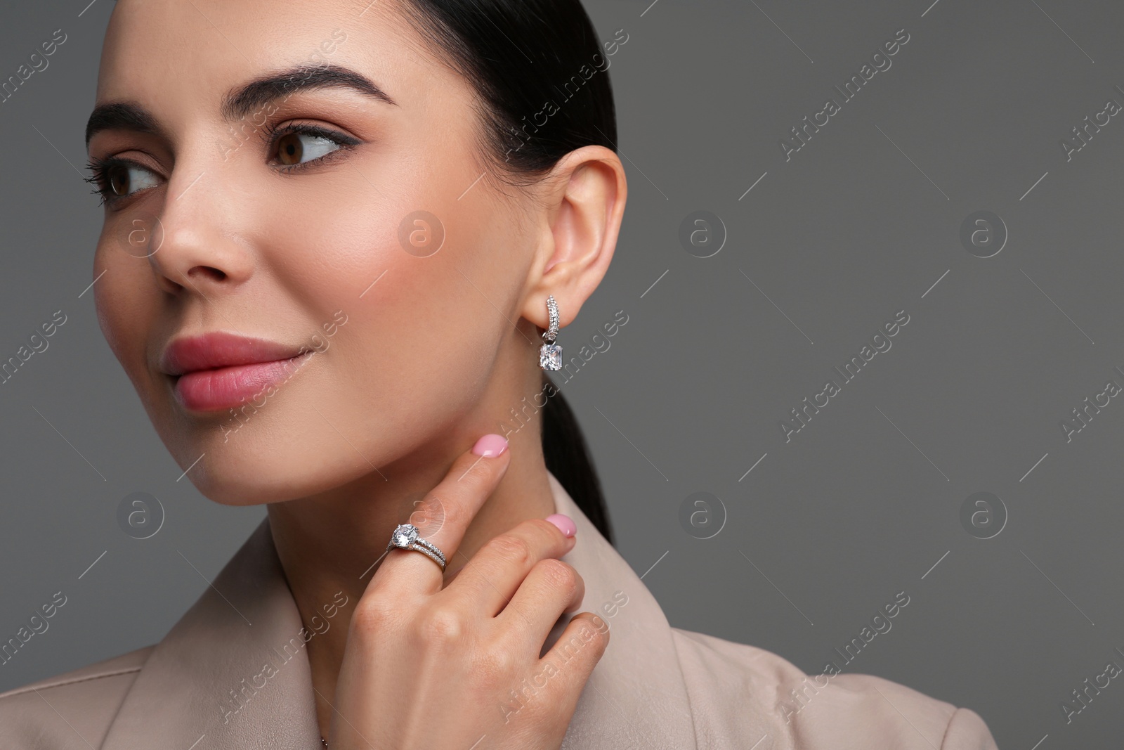 Photo of Young woman with elegant jewelry on dark grey background, closeup. Space for text