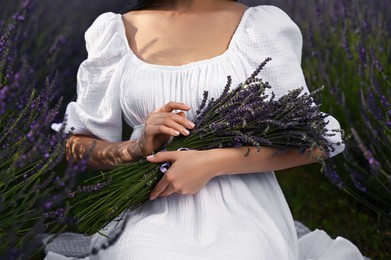 Woman with lavender bouquet sitting in field, closeup