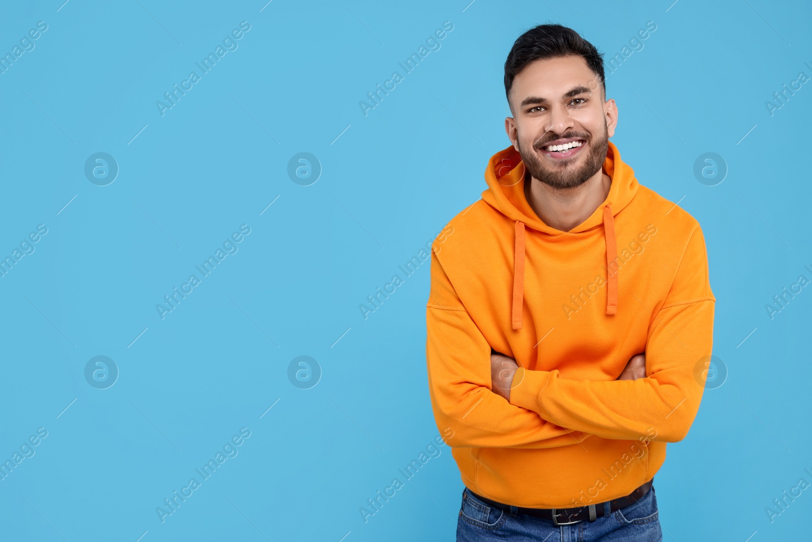 Photo of Handsome young man laughing on light blue background, space for text