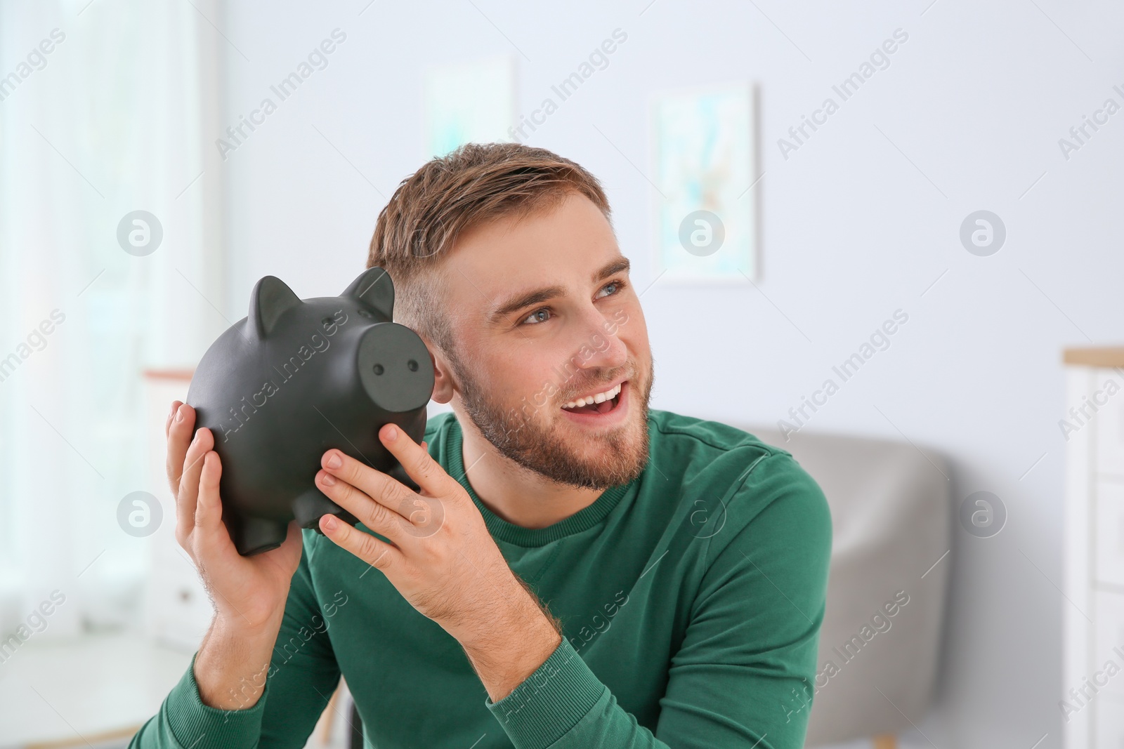 Photo of Young man with piggy bank on blurred background