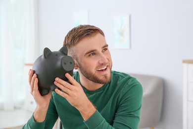 Young man with piggy bank on blurred background