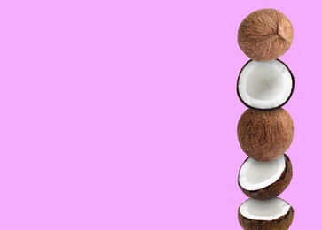 Stack of fresh coconuts on light fuchsia color background. Space for text