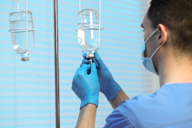 Photo of Nurse setting up IV drip in hospital, selective focus