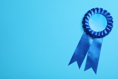 Photo of Blue award ribbon on turquoise background, top view. Space for text