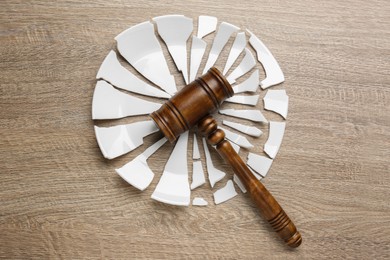 Divorce concept. Broken plate and gavel on wooden table, flat lay
