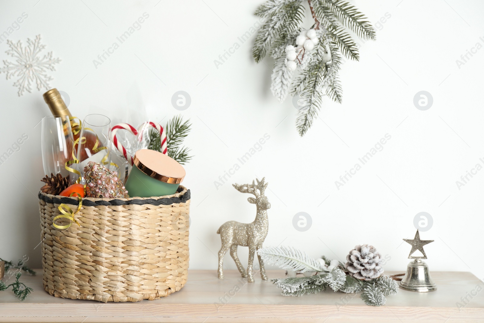 Photo of Wicker basket with gift set and Christmas decor on wooden table